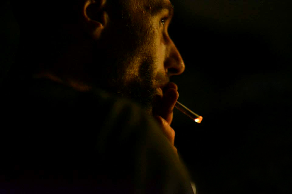 artist Kenneth Kenisman smoking a cigarette in close up side view