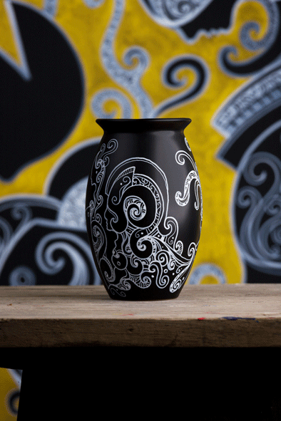 Black vase in a modern minimalistic shape, contains a beautiful hand drawn artwork with with acrylic paint by artist kennetn kenisman. The artwork on the object depicts a nature scene, with curls, waves, sea or nature elements and intricate details. Also silhouette figures wearing an ancient helmet. The composition is well balanced.